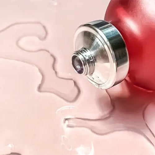 Red bottle with silver cap on a pink background