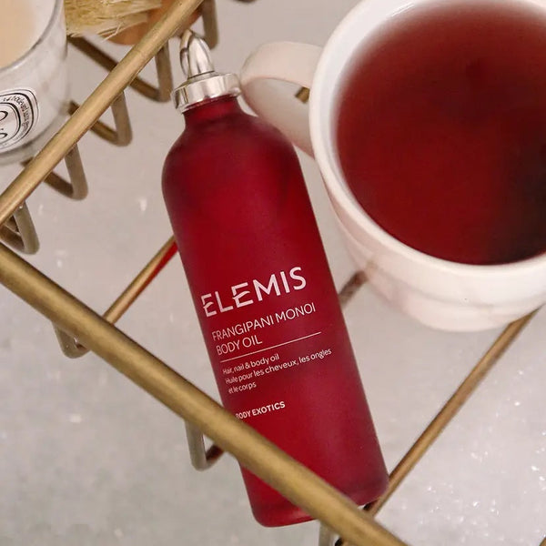 red elemis frangipani monoi body oil in bathtub with tea cup