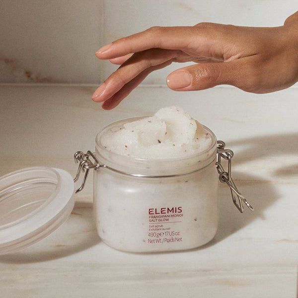 Person wrapped in a towel with skincare products on a marble surface