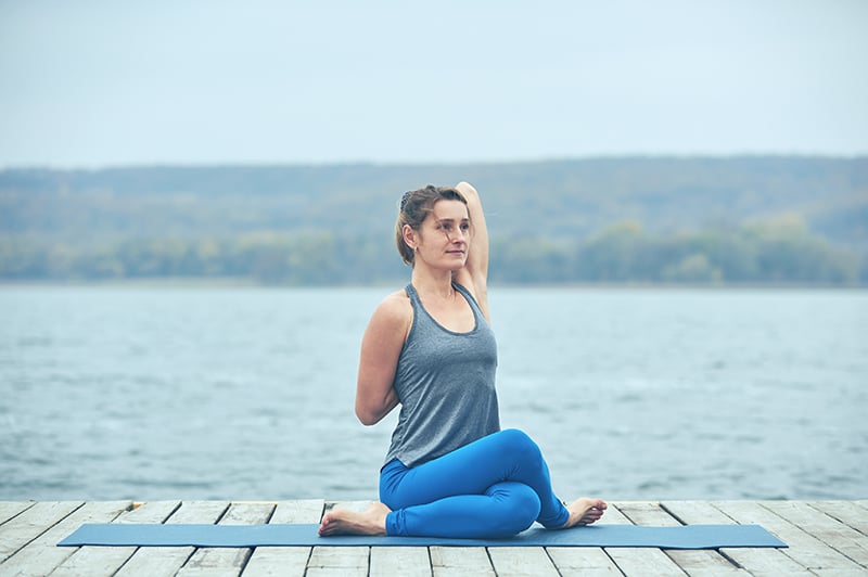 Young Slim Woman In Tight Sportswear Sitting On Orange Yoga Mat